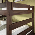 Dark walnut wood bunk bed with horizontal guardrails, white quilted bedding and green accent pillows against a pale green bedroom wall