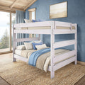 Whitewashed wooden bunk bed with blue and neutral bedding in a coastal bedroom by a large window and jute rug