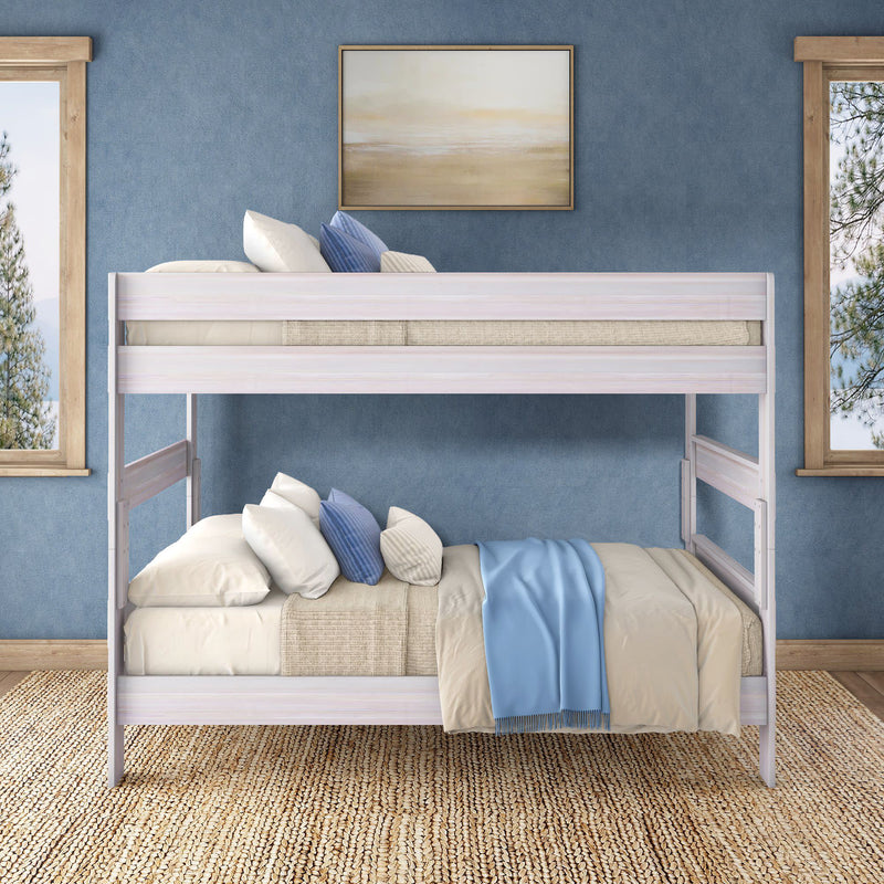 Whitewashed wooden twin-over-full bunk bed in blue coastal-style bedroom with beige bedding, blue throw blanket, jute rug and window views