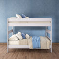 White wooden bunk bed with beige bedding, blue throw and pillows in a modern kids' bedroom with hardwood floor and textured blue wall