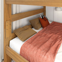 Wooden bunk bed lower mattress with rust-red textured blanket, tan pillows and white sheet in a modern bedroom setting
