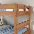 Solid wood twin-over-twin bunk bed with natural finish, safety rails and blue bedding in a modern cozy bedroom