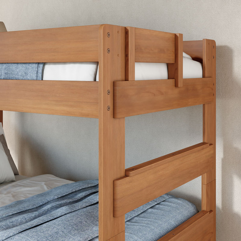 Solid wood twin-over-twin bunk bed with natural finish, safety rails and blue bedding in a modern cozy bedroom