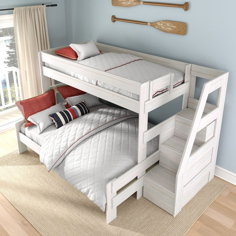 White wooden full-over-twin bunk bed with built-in storage staircase, quilted white bedding and red-navy striped accent pillows in a coastal kids' bedroom with light blue wall and wooden oar décor.