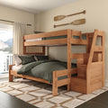 Solid wood twin-over-full bunk bed with built-in storage staircase, green bedding and oar wall decor in cozy lakeside bedroom with natural light