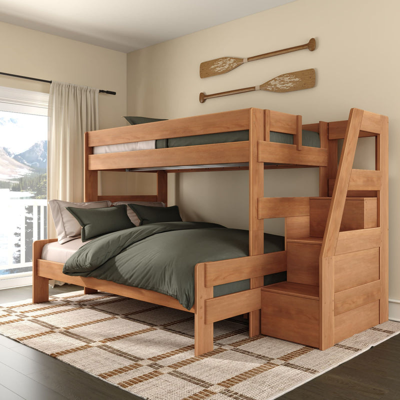 Solid wood twin-over-full bunk bed with built-in storage staircase, green bedding and oar wall decor in cozy lakeside bedroom with natural light