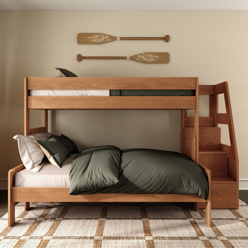 Modern wooden bunk bed with side staircase storage, dark green bedding and pillows in a cozy coastal-style kids’ bedroom with decorative wooden oars on the wall