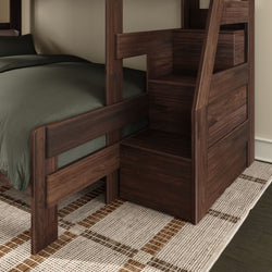 Dark walnut wooden bunk bed with built-in storage staircase, green bedding and woven area rug in modern bedroom
