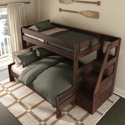 Twin-over-full dark wood bunk bed with built-in storage staircase, green bedding and pillows, plaid area rug, paddle wall decor and lake-view window in a cozy cabin-style bedroom