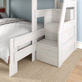 White wooden bunk bed with built-in storage staircase and safety rail, twin mattress with quilted white comforter on beige rug against light blue wall, modern kids bedroom furniture