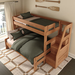 Twin-over-full solid wood bunk bed with built-in staircase storage, natural wood finish and green bedding in a cozy coastal-style bedroom with oar wall decor and balcony view