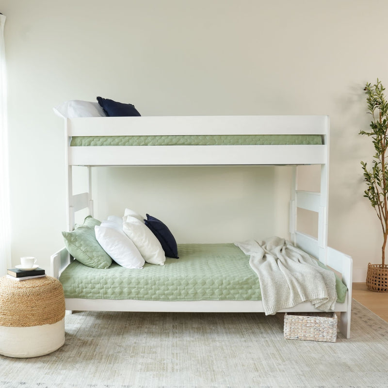 White bunk bed with green bedding and pillows in a cozy bedroom setting.