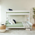 White bunk bed with green bedding and pillows in a cozy bedroom setting.