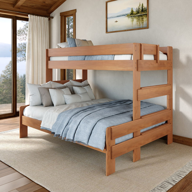 Solid wood twin-over-full bunk bed in a rustic mountain bedroom with light-blue bedding, white pillows, and large windows showing a lake and pine trees