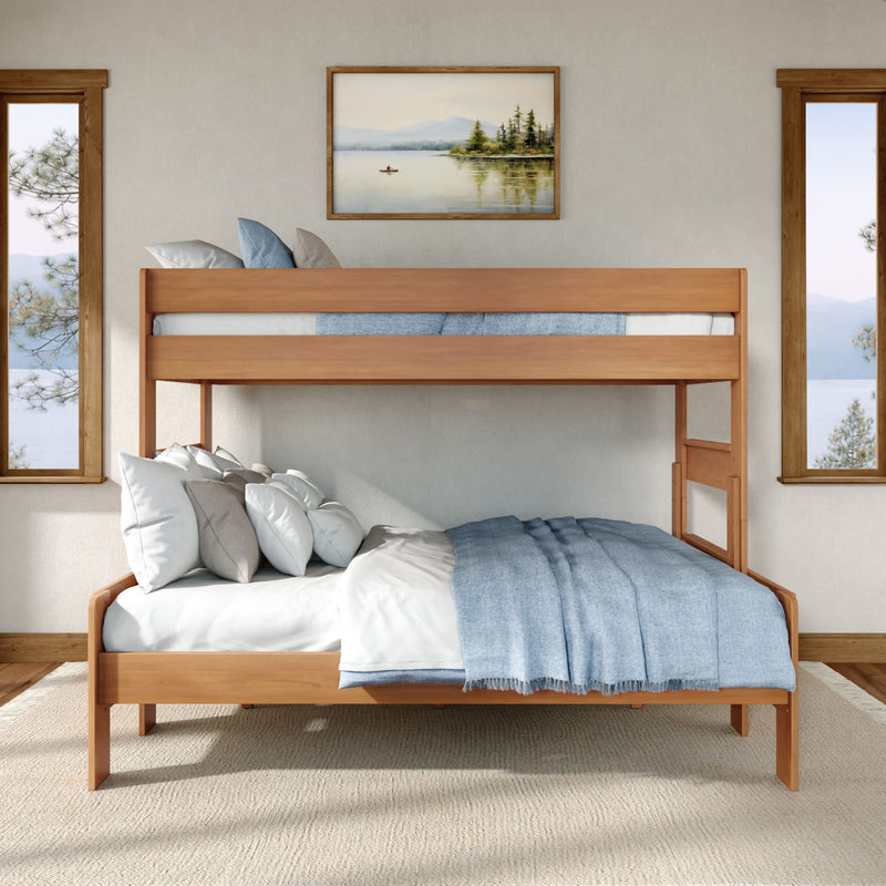 Modern wooden twin-over-full bunk bed with blue and white bedding in a bright lakeside bedroom with large windows, neutral walls, framed landscape art, and natural wood flooring