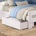 Light wood trundle bed with beige duvet, blue throw blanket, striped pillows and woven jute rug in coastal bedroom