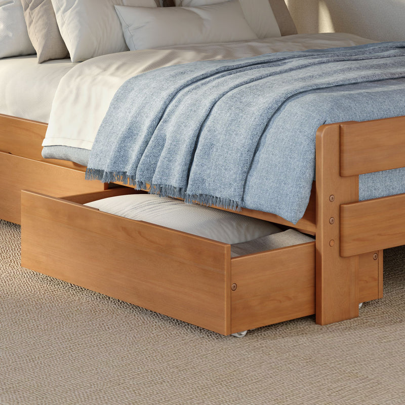 Wooden trundle bed with light blue woven throw blanket, white linens and under-bed storage drawer in a cozy modern bedroom