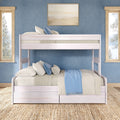 Coastal bedroom with light wood bunk bed, layered pillows and blue throw, abstract wall art, large windows and woven jute rug
