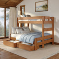 Sunlit wooden bunk bed with pull-out trundle drawers and blue linens in a cozy cabin bedroom with large windows and lake painting