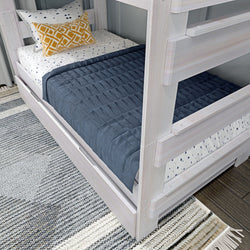 White wooden bunk bed with blue quilt and decorative pillows in a modern bedroom setting.