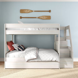 White wooden twin-over-full bunk bed with staircase in a coastal kids' bedroom, light blue wall, quilted white bedding, throw pillows and decorative wooden oars