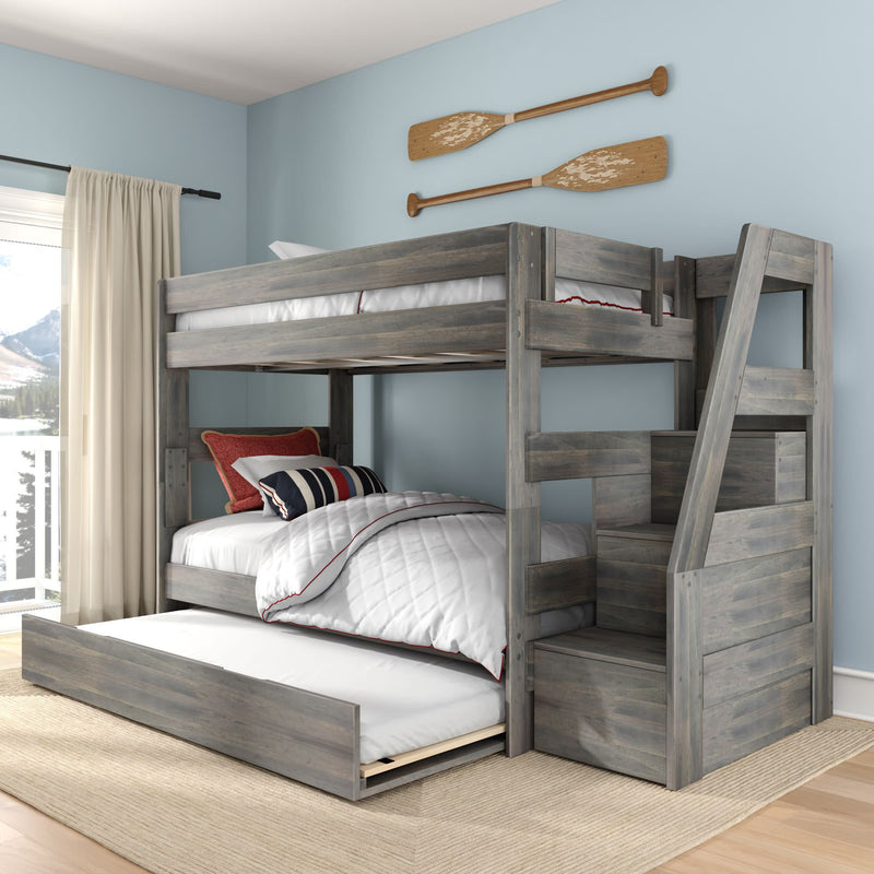 Gray wooden bunk bed with pull-out trundle and stair-storage, coastal kids' bedroom design with blue walls, striped pillows and mountain-view window