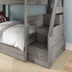 Gray weathered wood bunk bed with built-in storage staircase and drawers, white quilted comforter with red piping and striped pillow in a kids' bedroom