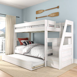 White wooden bunk bed with pull-out trundle and staircase in coastal kids' bedroom with light blue walls and nautical oars wall art