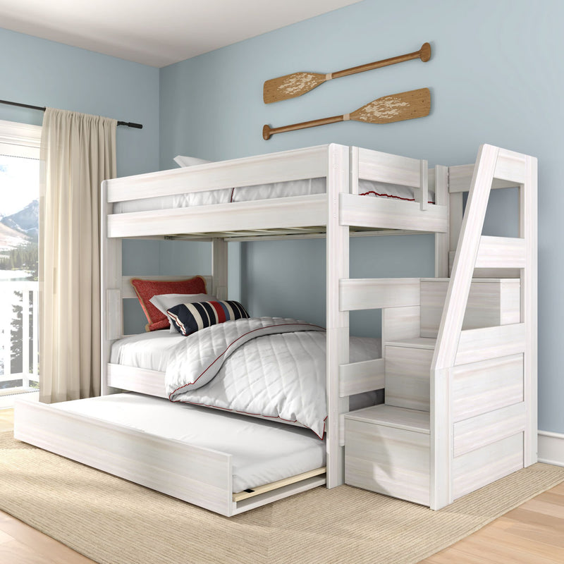 White wooden bunk bed with pull-out trundle and stair storage in a coastal-style kids bedroom with light blue walls, quilted bedding, striped pillows and decorative wooden oars