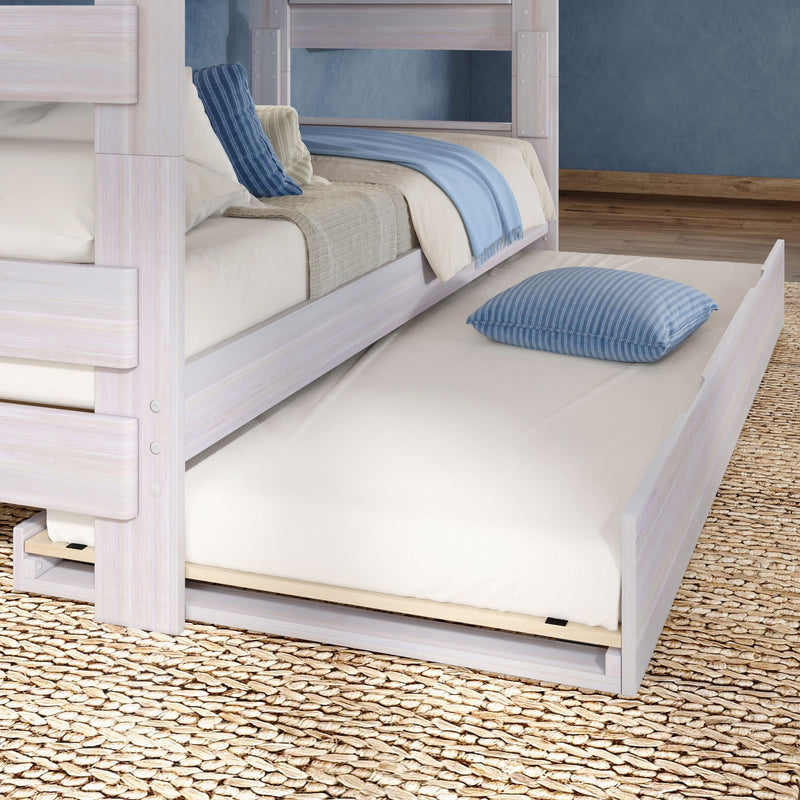 Whitewashed wooden bunk bed with pull-out trundle mattress, blue striped pillow on woven rug — space-saving kids bedroom furniture