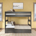 Dark gray wooden twin-over-full bunk bed with beige bedding and plaid pillows in a cozy yellow-walled bedroom with lake artwork and windows
