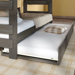 Trundle bed under a bunk bed with pull-out mattress and plaid pillow, dark wood frame and neutral bedding on a patterned rug