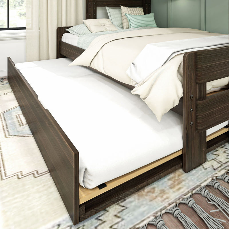 Dark wooden bed with pull-out trundle and cozy bedding in a bright bedroom setting.