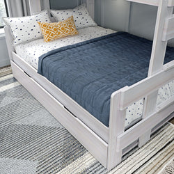 White bunk bed with navy blanket and patterned pillows in modern bedroom setting.
