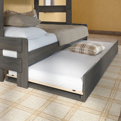Pull-out trundle bed with mattress and plaid pillow under a gray wood bunk bed in a neutral beige bedroom — space-saving guest bed and underbed storage solution