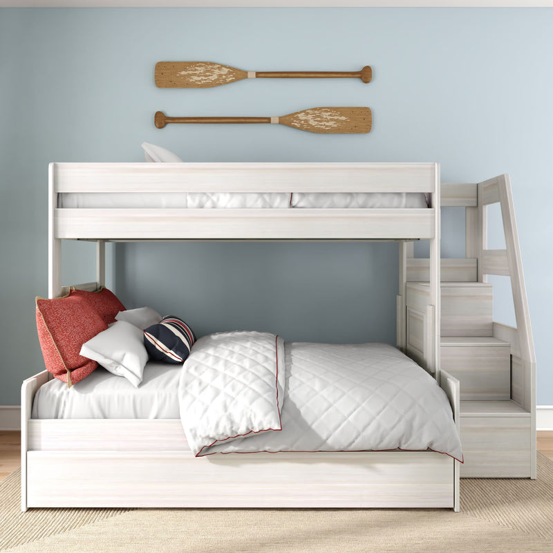 White wooden bunk bed with staircase and trundle in coastal kids bedroom, light blue wall with decorative wooden oars, quilted white bedding and red accent pillows