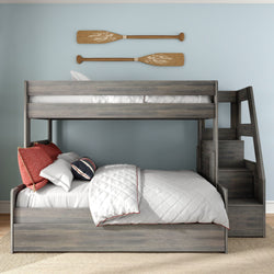 Gray wood twin-over-full bunk bed with staircase storage, white quilted bedding with red trim, red and striped pillows, nautical oar wall decor on light blue kids' bedroom