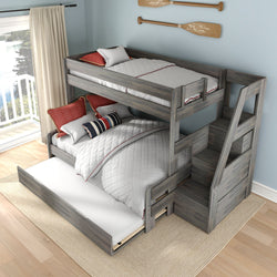 Gray wooden bunk bed with trundle and built-in staircase storage, white quilted bedding and red pillows in bright coastal bedroom with balcony lake view