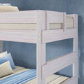 Whitewashed wooden bunk bed close-up with light blue bedding and striped pillows in a modern kids' bedroom against a blue textured wall