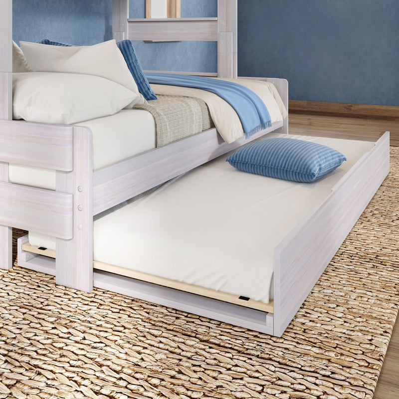 Whitewashed wood bed with pull-out trundle mattress, blue throw and striped pillow on woven jute rug