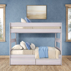 Whitewashed wooden bunk bed with blue and beige bedding in a coastal-style kids’ bedroom, textured blue wall, framed art and natural light