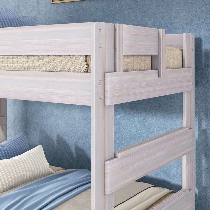 Whitewashed wooden bunk bed with safety rails, blue bedding and striped pillows in a modern kids' bedroom