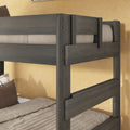 Gray solid wood bunk bed frame with twin mattresses, beige bedding and brown pillows against yellow wall, rustic close-up