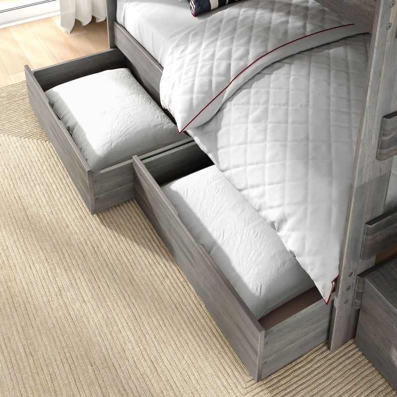 Gray wooden bunk bed with under-bed pull-out storage drawers holding white pillows and quilted white bedding on a beige rug — space-saving kids bedroom storage solution