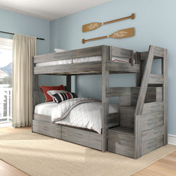 Gray wooden bunk bed with built-in staircase and storage drawers in coastal bedroom with light blue walls and oar wall decor