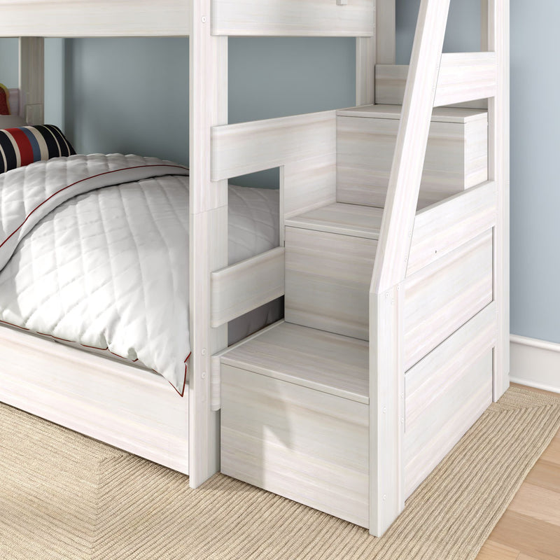 Whitewashed wooden bunk bed with built-in storage stair drawers and lower twin bed with quilted bedding in a kids' room