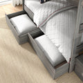 Grey weathered wood bunk bed with built-in pull-out under-bed storage drawers, white quilted bedding with red piping and pillows on a natural woven rug in a bright modern children's bedroom