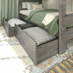 Gray wooden bed with storage drawers underneath, featuring green bedding and decorative pillows, on patterned area rug.