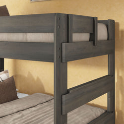Close-up of a sturdy gray solid-wood bunk bed frame with neutral beige bedding and pillows against a warm textured yellow wall.