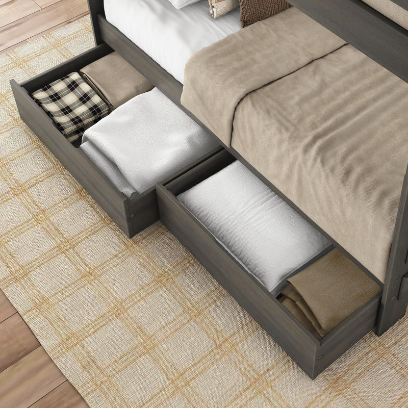 Gray wood platform bed with built-in under-bed storage drawers holding folded blankets, pillows, and linens in a neutral bedroom